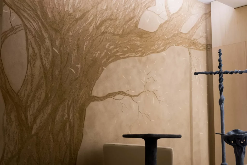 Peinture murale d'un arbre à côté d'une croix stylisée.