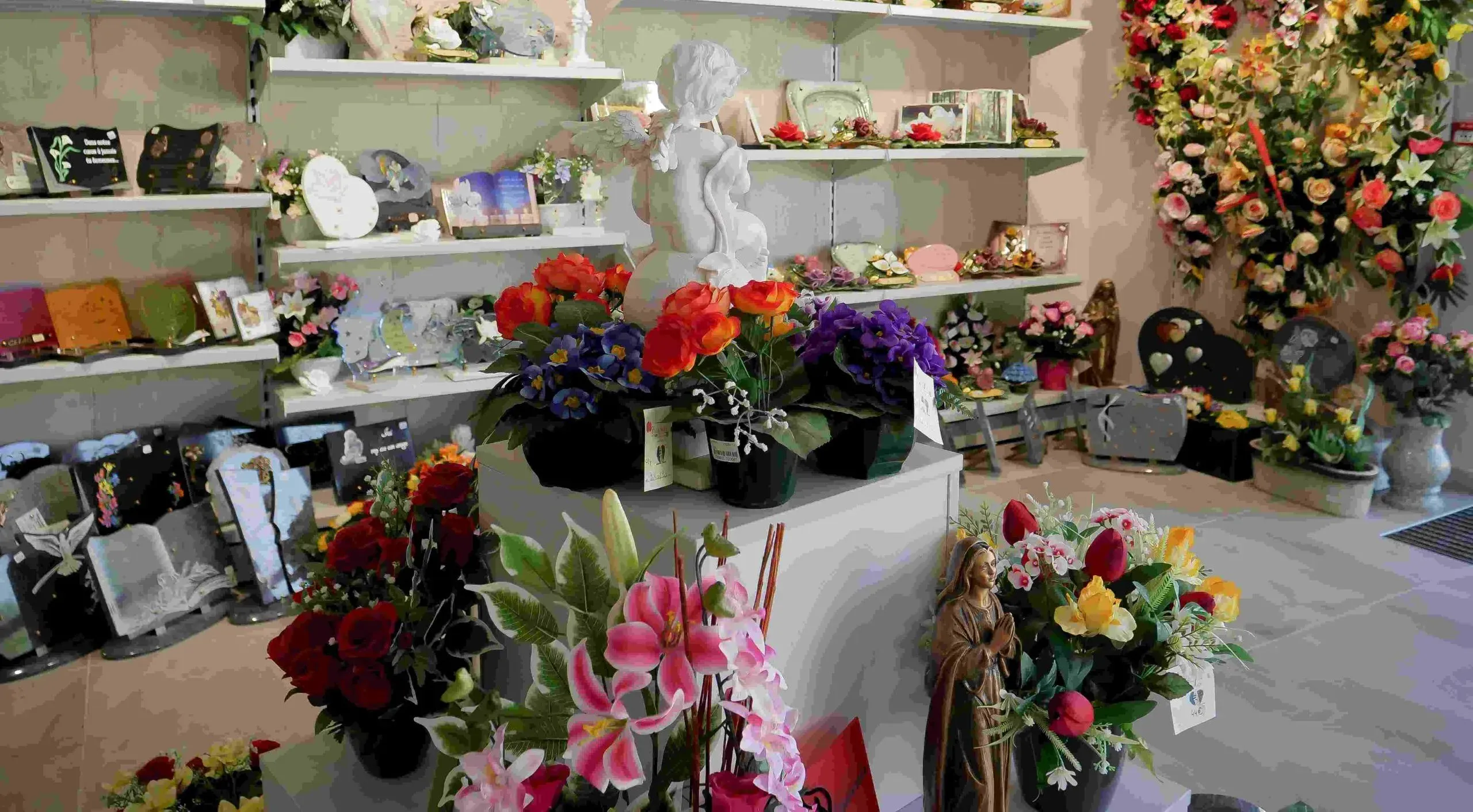 Intérieur de boutique funéraire présentant des fleurs artificielles et des plaques.